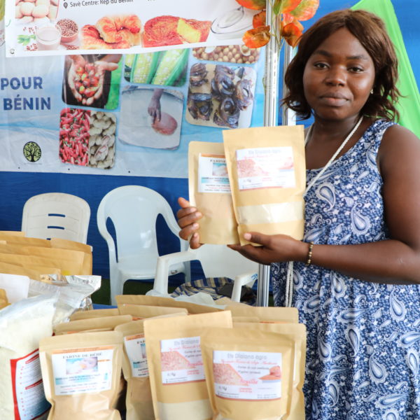 A woman stands with products at a market