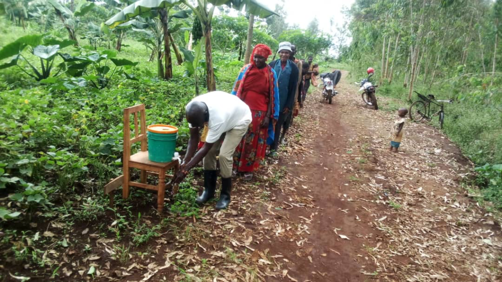 Burundian farmers line up to wash hands at a field day