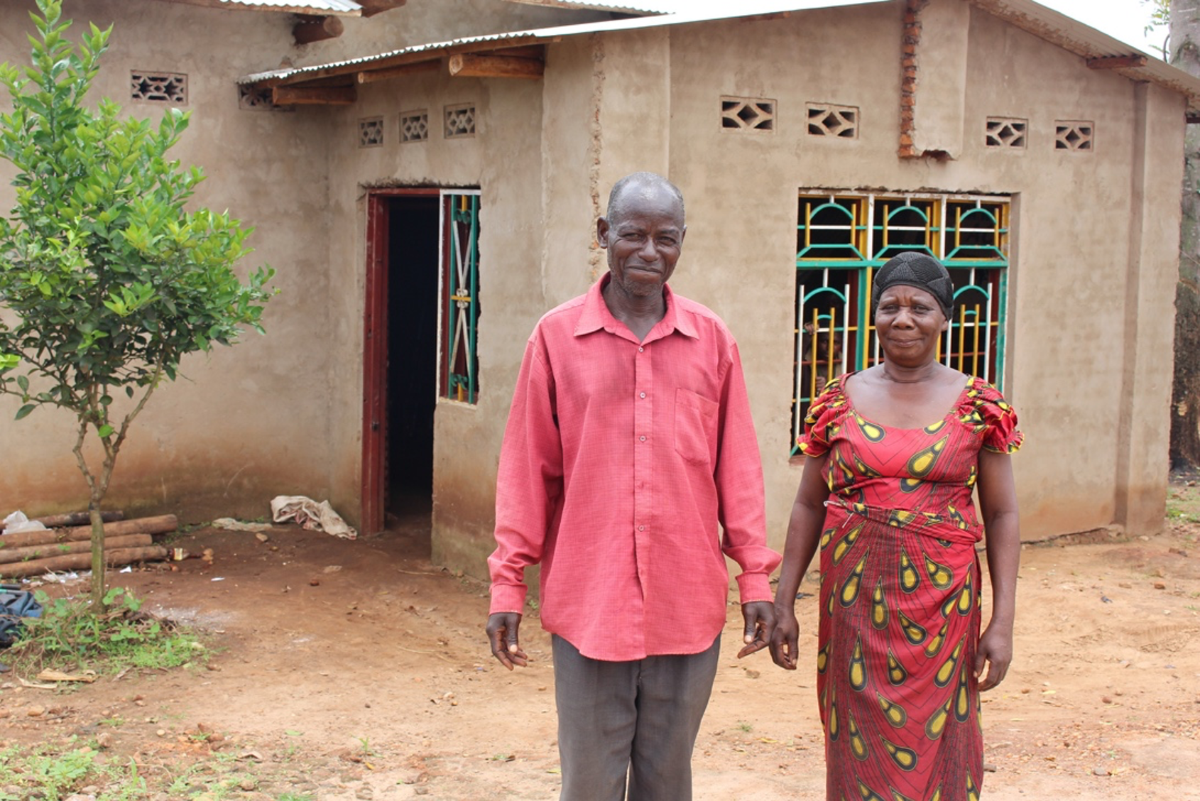Angeline and Alphonse stand in front of their house