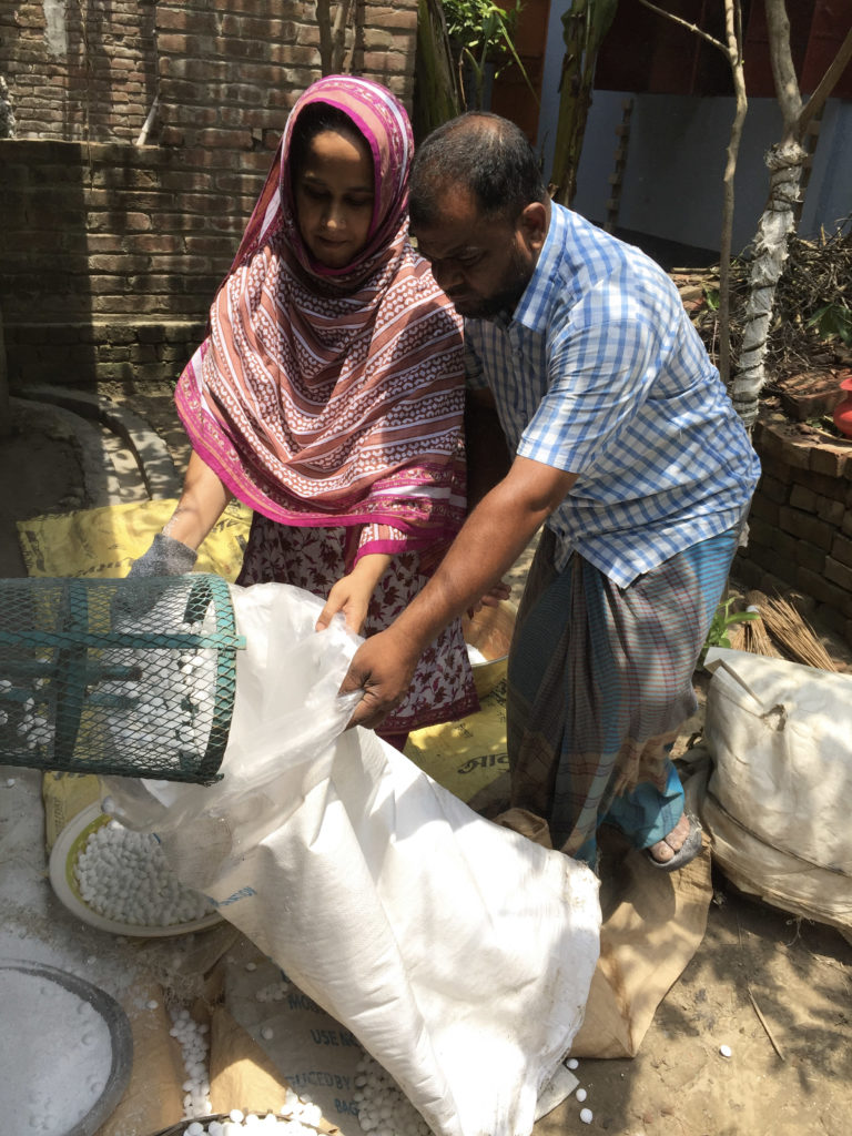 Man and woman collecting briquettes from machine