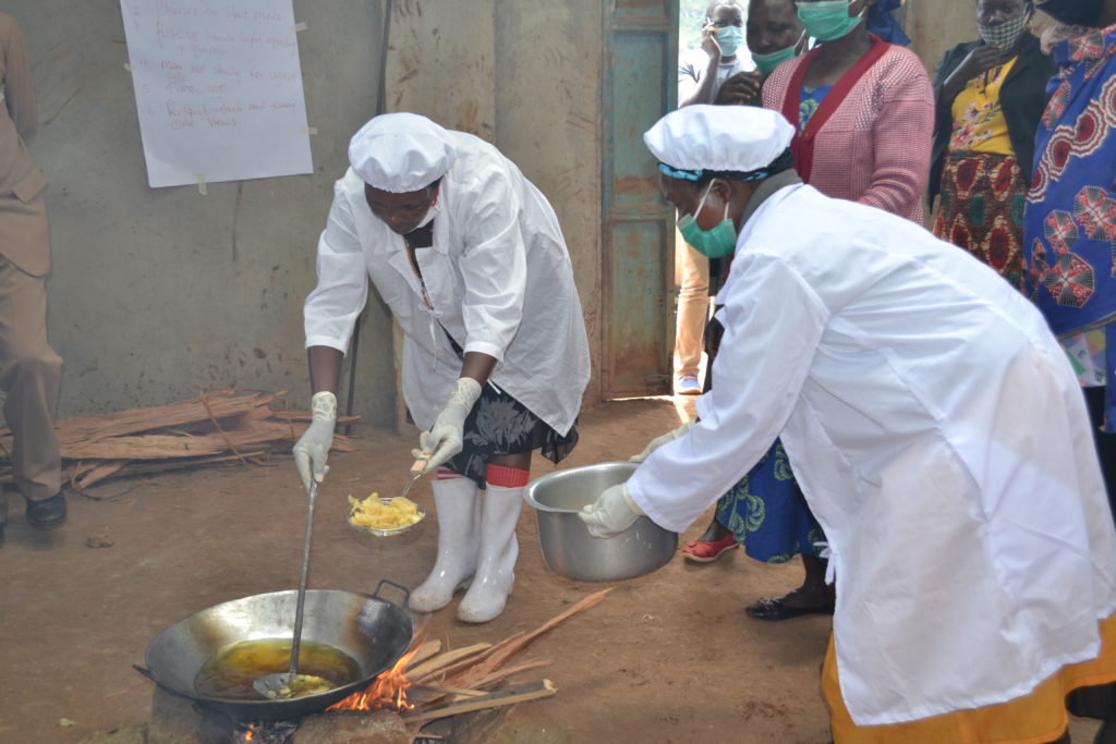 Women cooking crisps over an outdoor fire