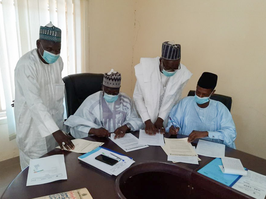 Project leaders sit around a table and sign a document