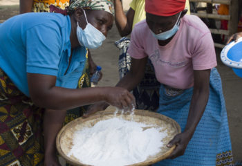 Women processing rice into flour for selling at local markets in Buzi