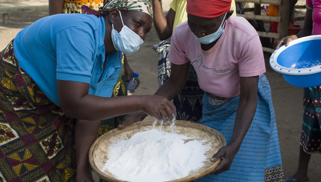 Women processing rice into flour for selling at local markets in Buzi