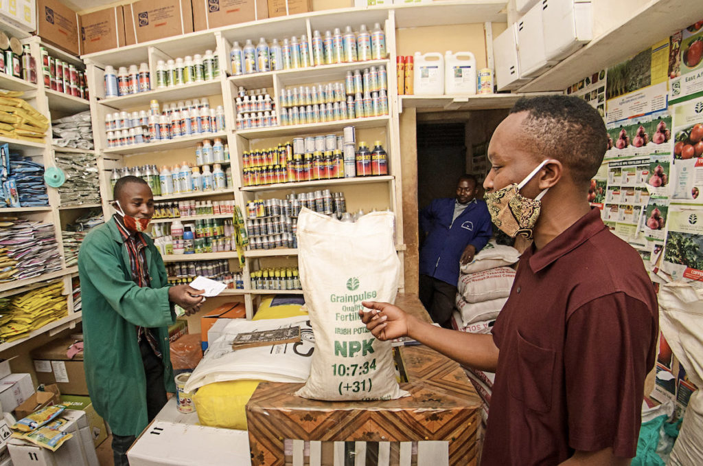 Men exchange money during the sale of a fertilizer bag