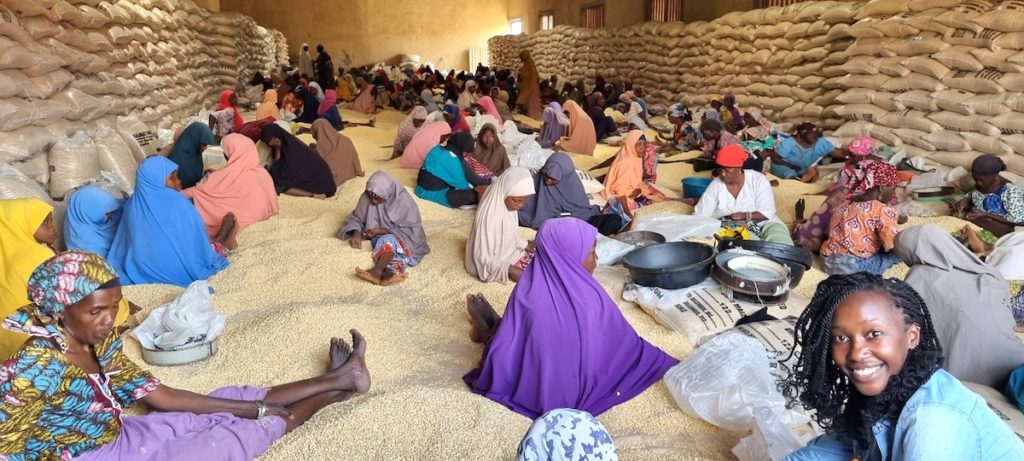 A woman from the Tegemeo delegation visits with female grain processors in Nigeria