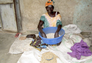 A woman from South Sudan sits as she shorts several bowls of seeds