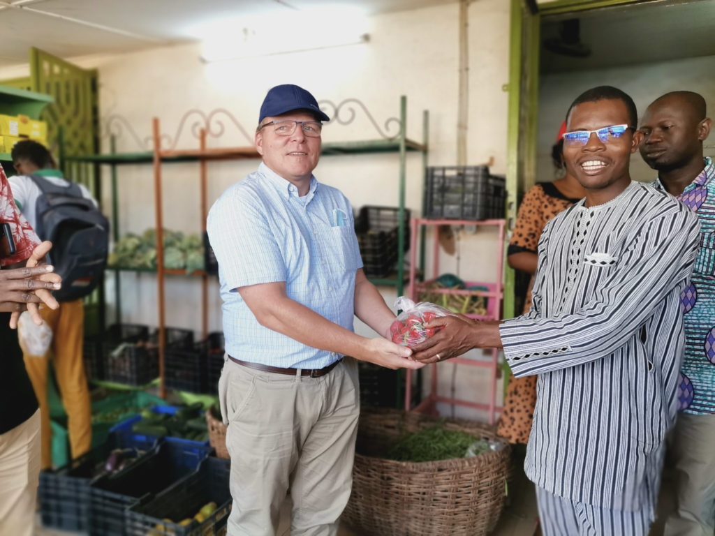 Henk poses with a representative from BioProtect. The pair hold a bag of strawberries between them.