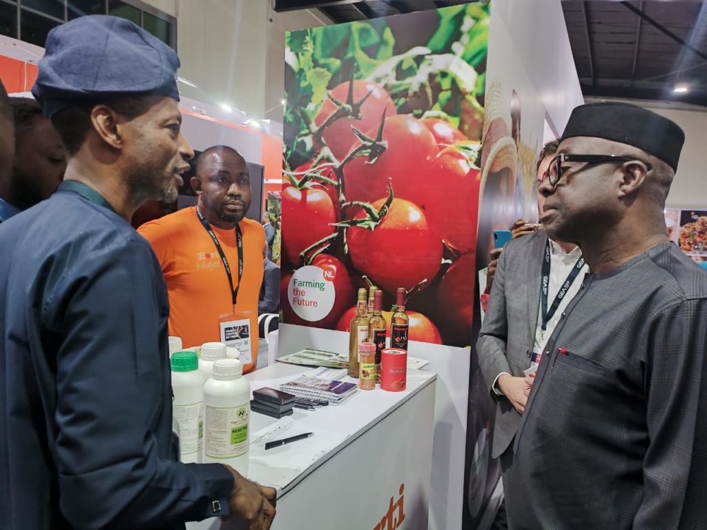 Program director (left) speaks with the minister of trade (right) in front of a conference booth