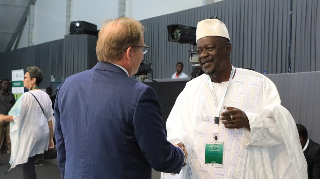 Henk van Duijn (left) meets an leader from Africa in white (right); they are shaking hands