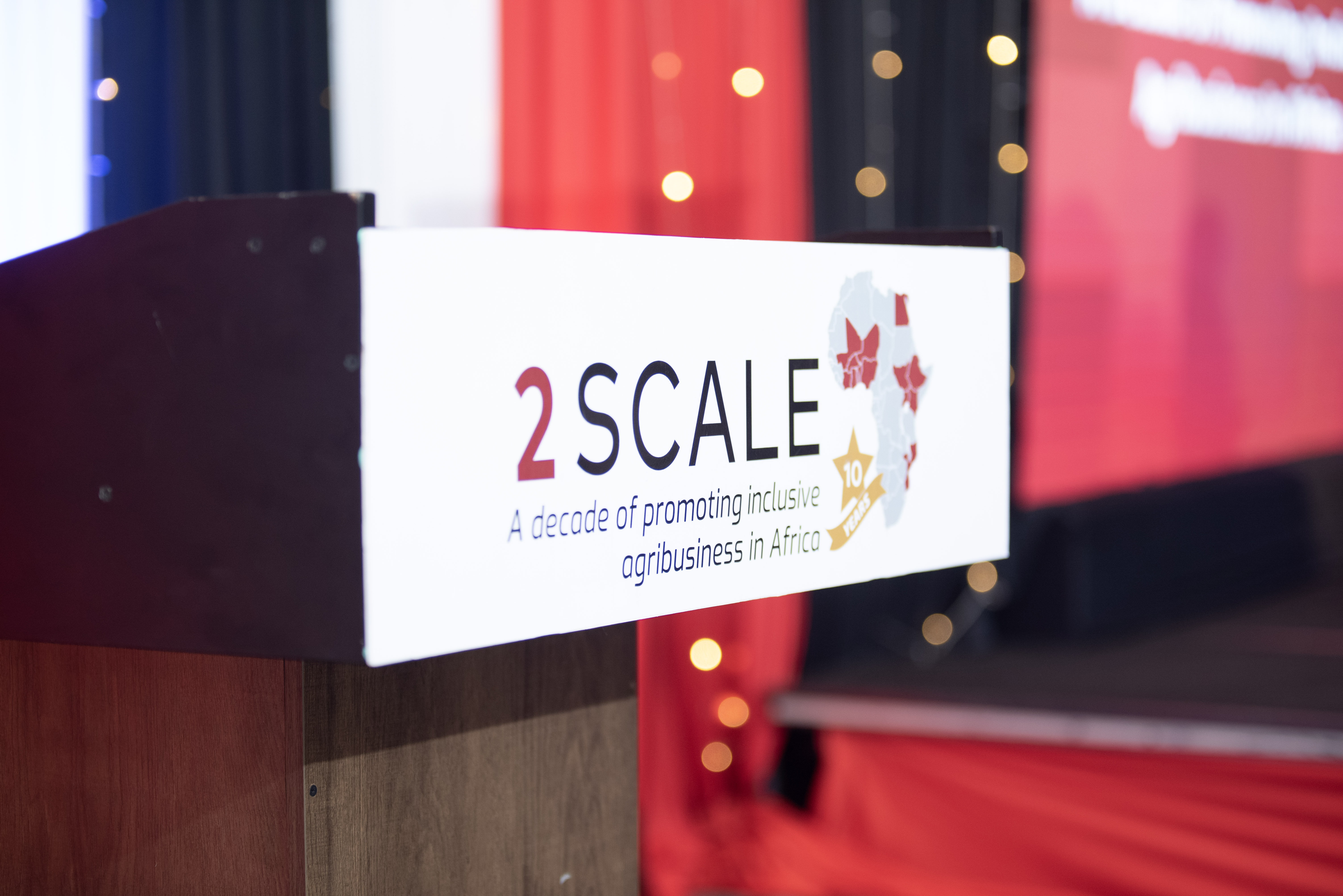The 2SCALE 10-year anniversary logo is displayed on a podium during the kickoff event.