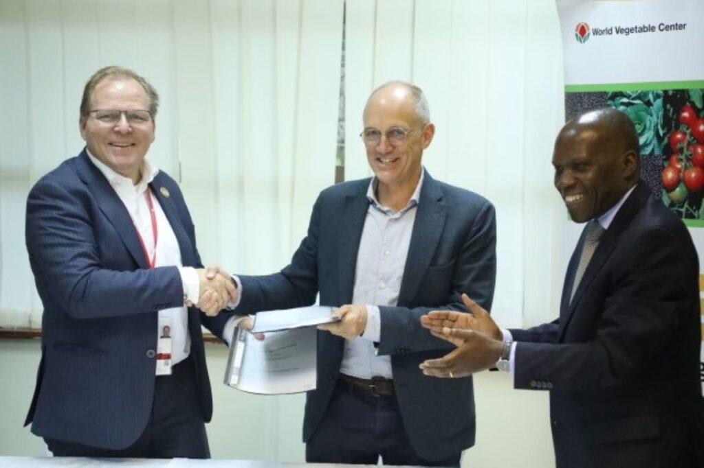 Henk van Duijn and Marco Wopereis shaking hands with Gabriel Rugalema applauding on the side.