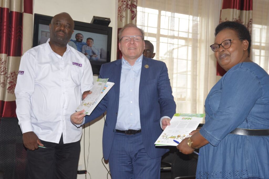 Hon. Richard Rwabuhinga, Kabarole District Chairman (Left), and Hon. Victoria Rusoke Busingye, Minister of State for Local Government (Right), receive IFDC's strategy document from the President and CEO Henk Van Duijn (Center).