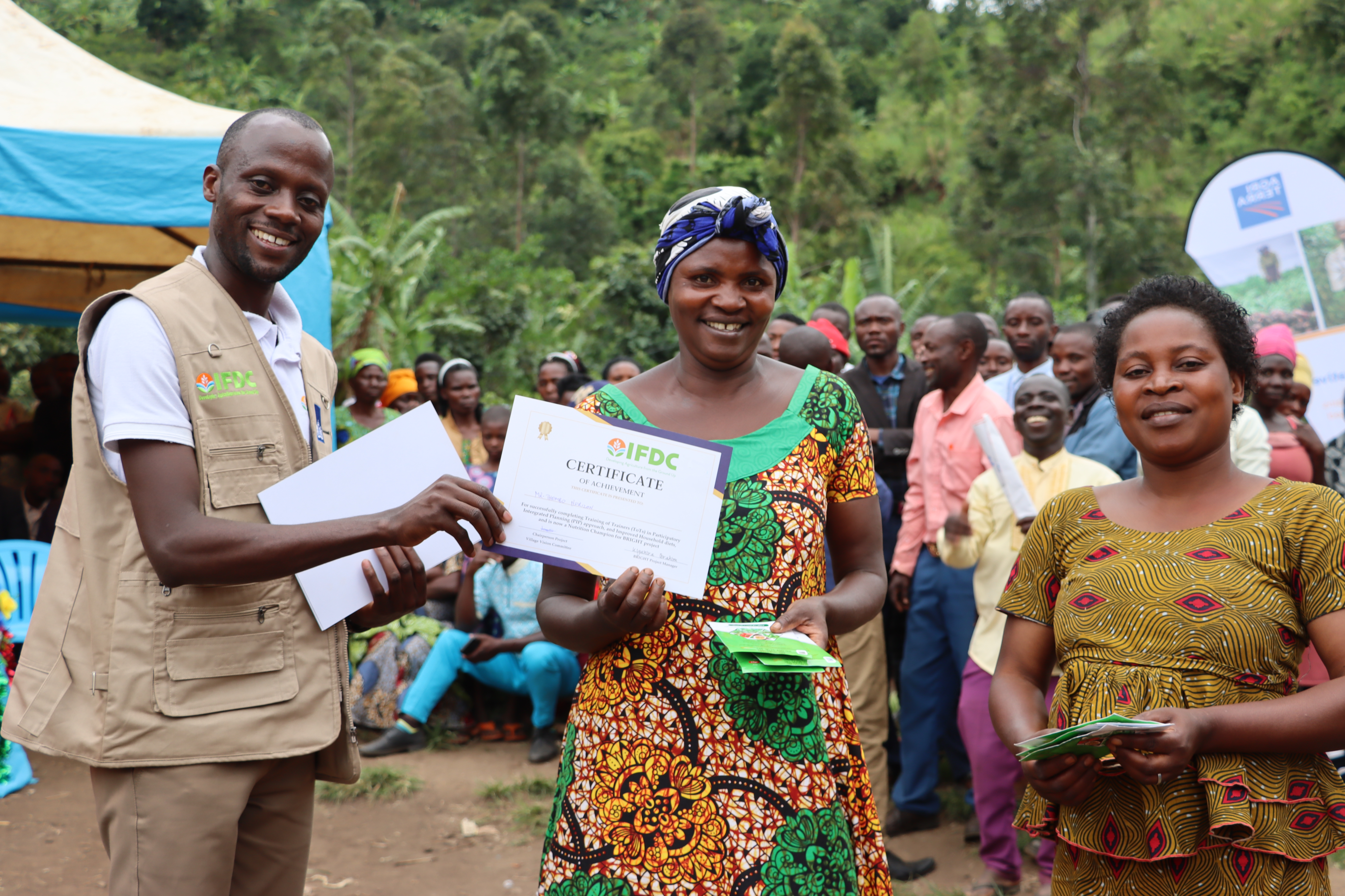 A group of three people, a man and two women to his right. The man is handing a certificate to the woman in the middle