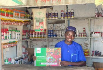 A young agripreneur at an agro input store holding the HortiNigeria Agrodealer Sales Logbook.