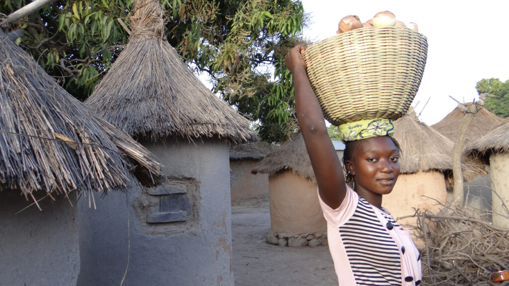 A woman holding a basket of onions.