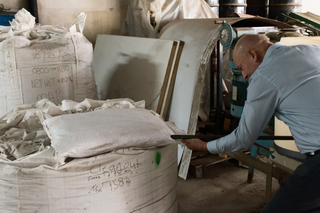 A man gathers fertilizer sample from a large bag.